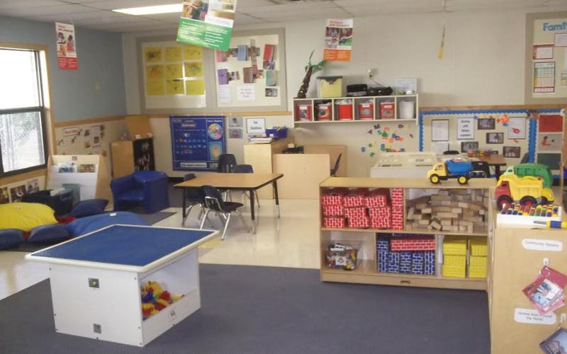 An empty early childhood classroom with various play areas and learning materials