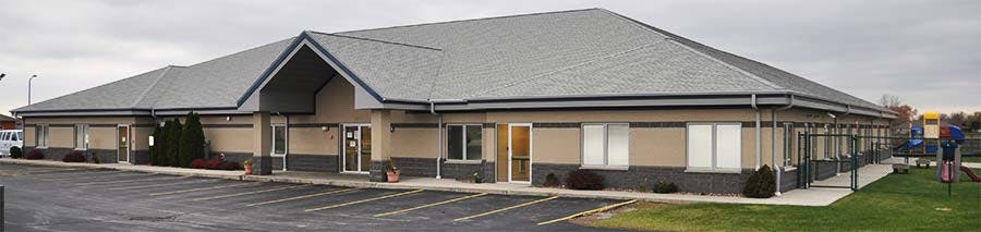 Exterior view of a long, single-story building with a gray roof