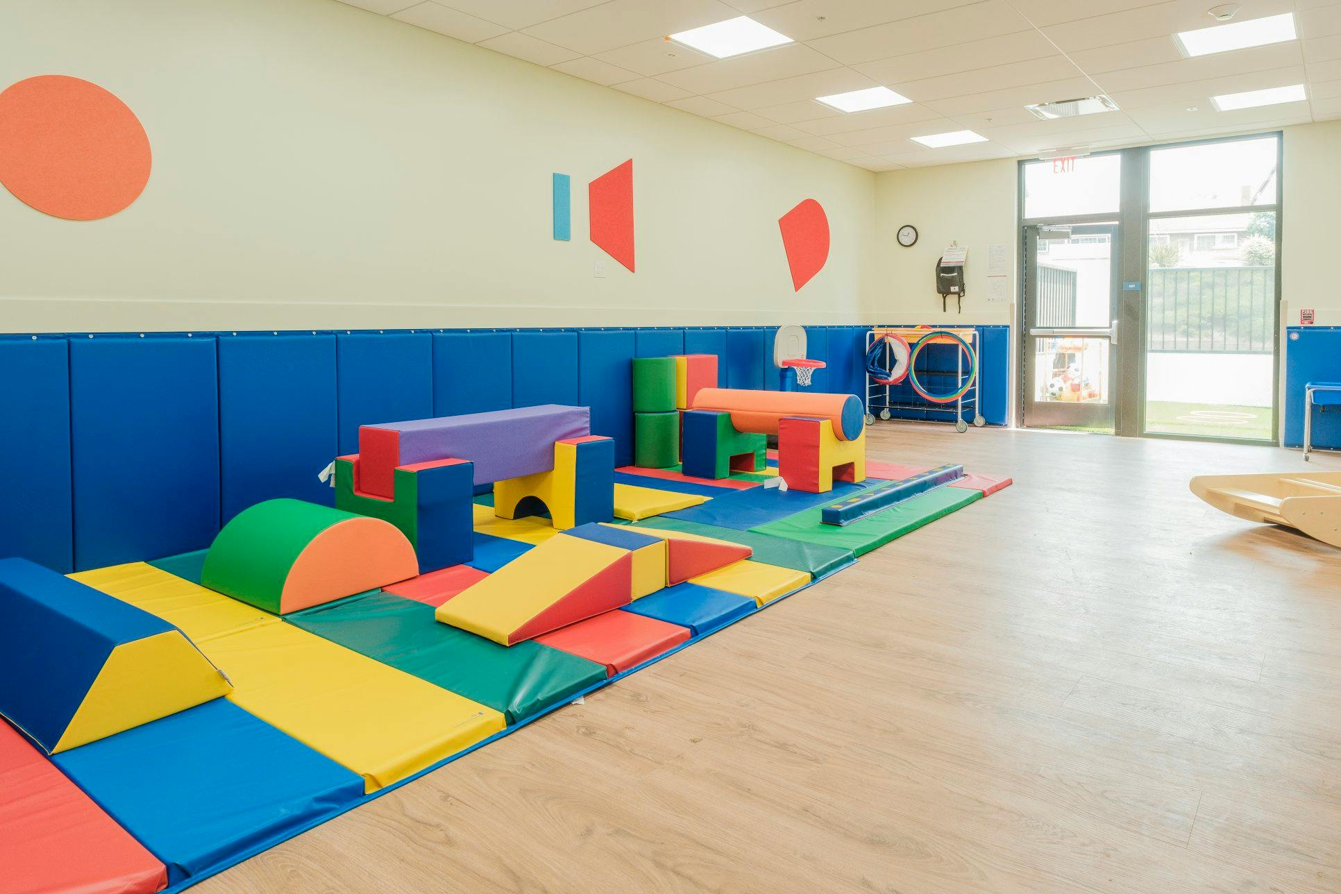 Colorful soft play equipment for children in a room with blue padded walls