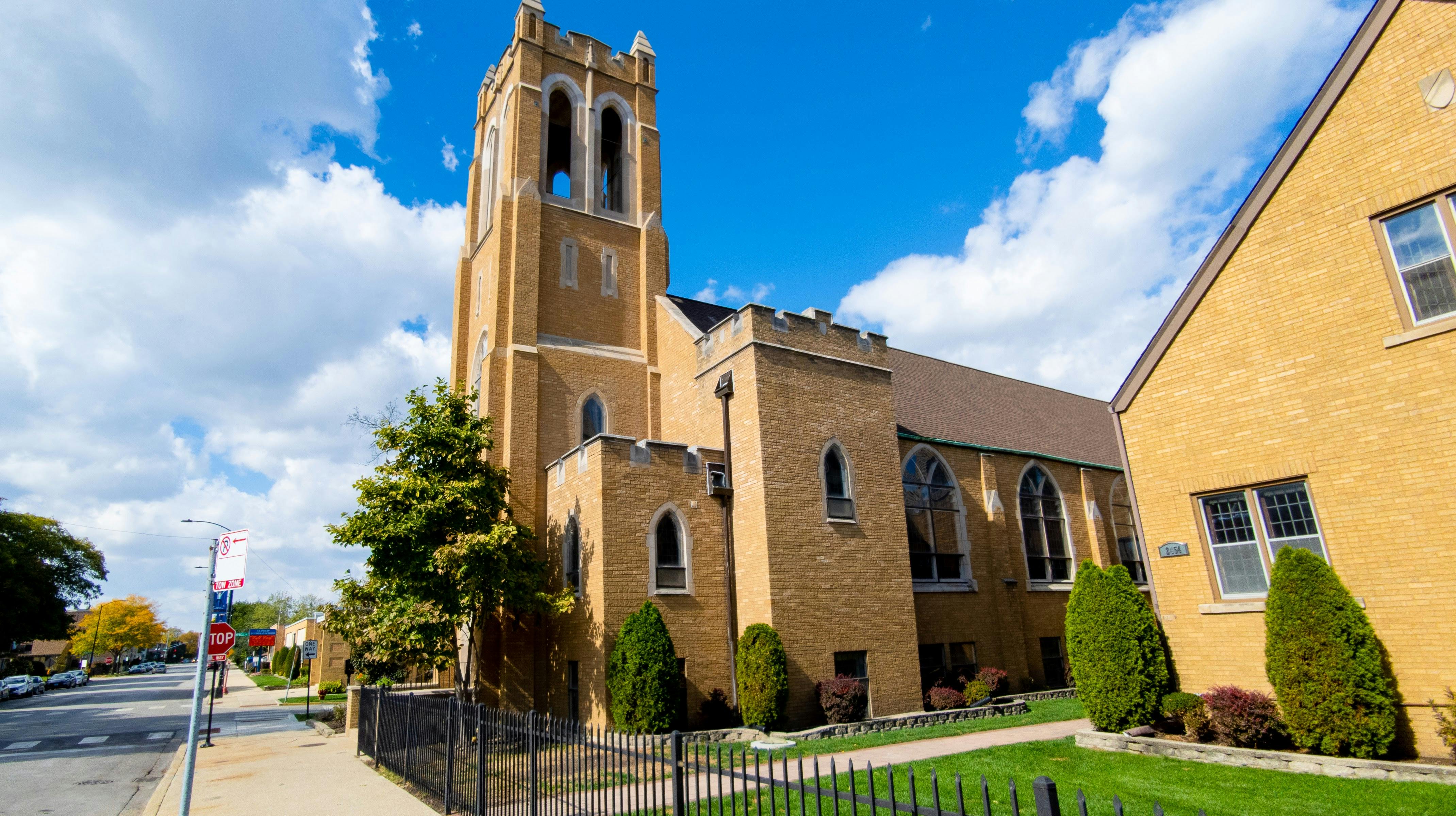 Brick church with a tall bell tower under a blue sky