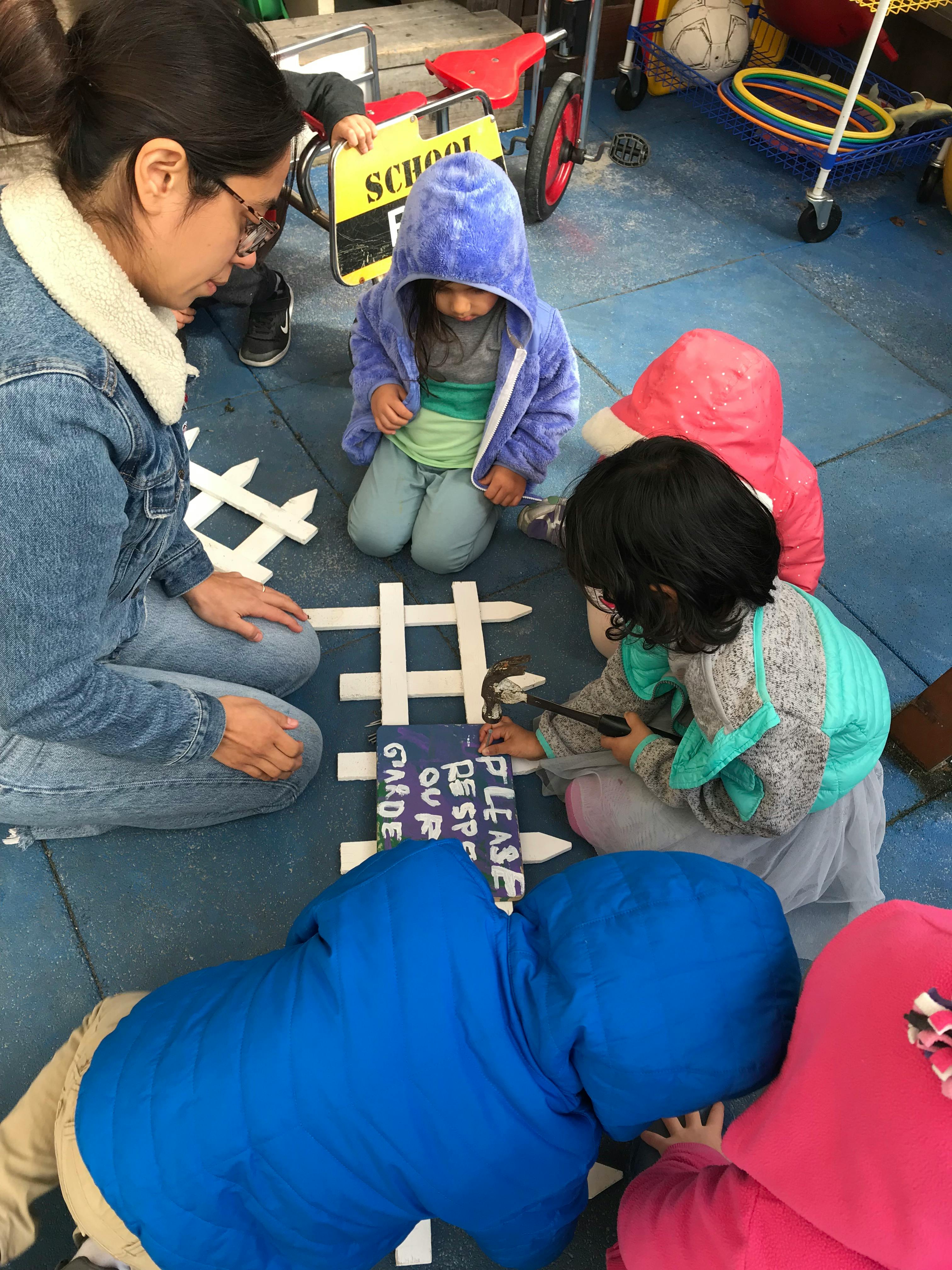 Adult and children gathered around a "Please Respect Our Garden" sign