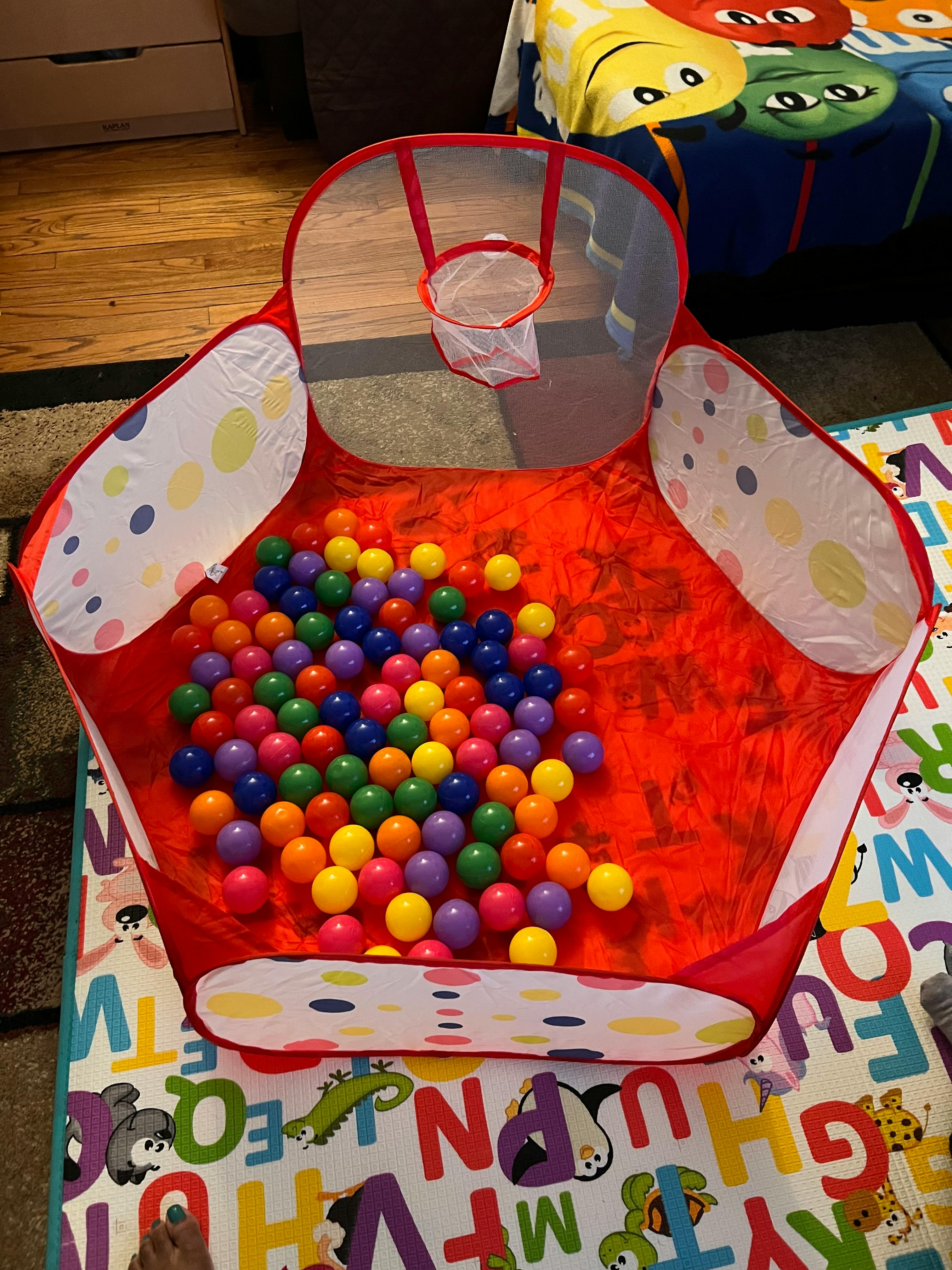 Red ball pit with colorful plastic balls and a small basketball hoop