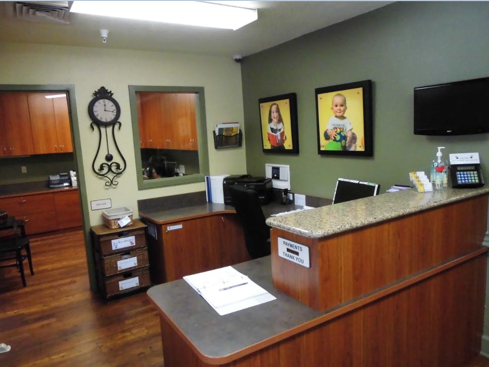 Reception desk with a computer, printer, and framed pictures on the wall