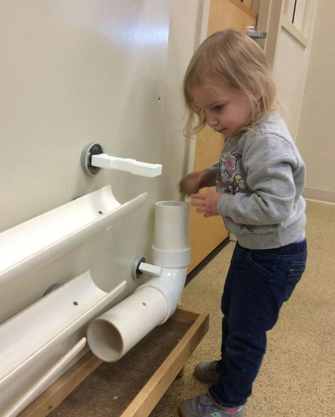 Child playing with a PVC pipe and gutter system