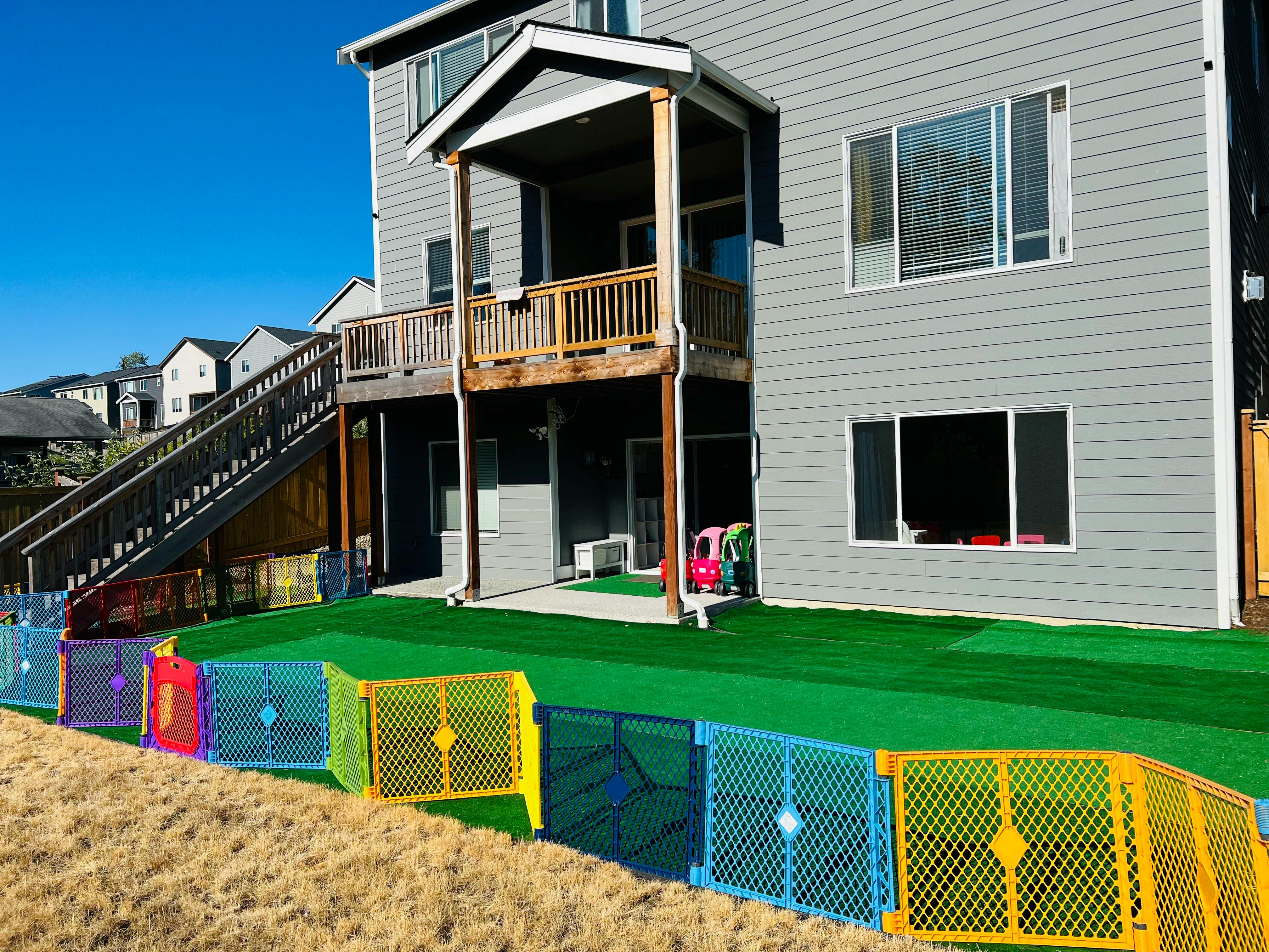 Colorful fence panels on a grassy slope in front of a house