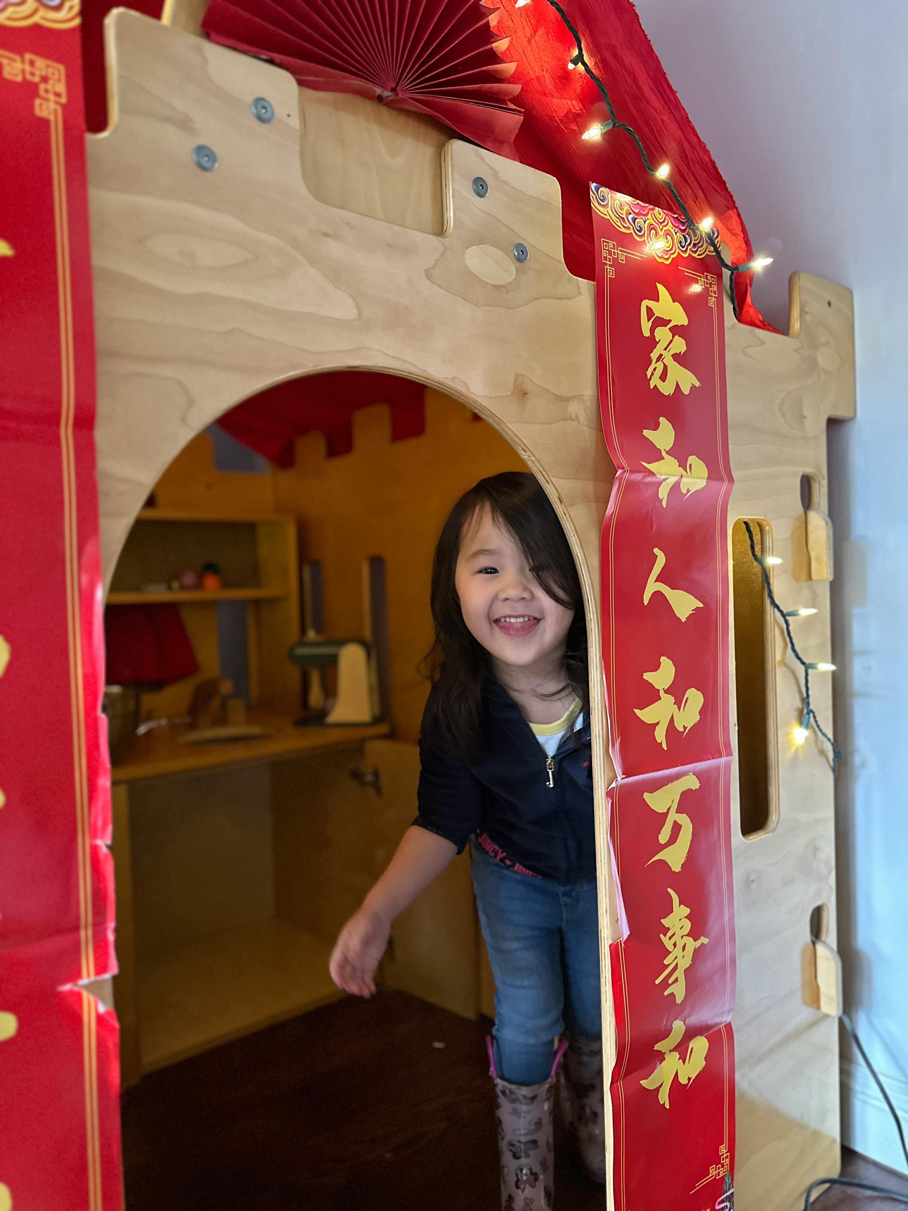 Child peeking out from a wooden playhouse