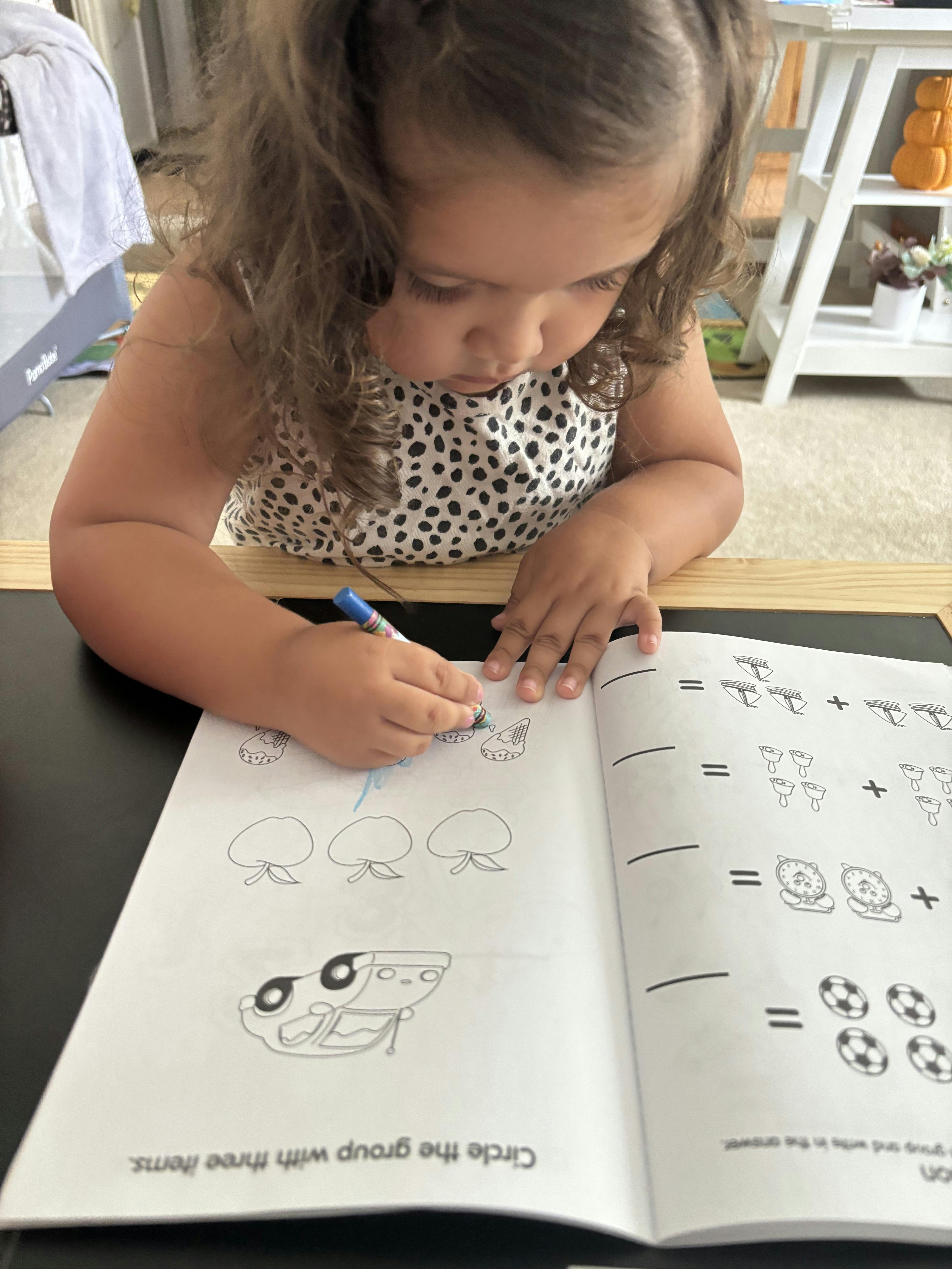 Child drawing in a workbook with a blue marker