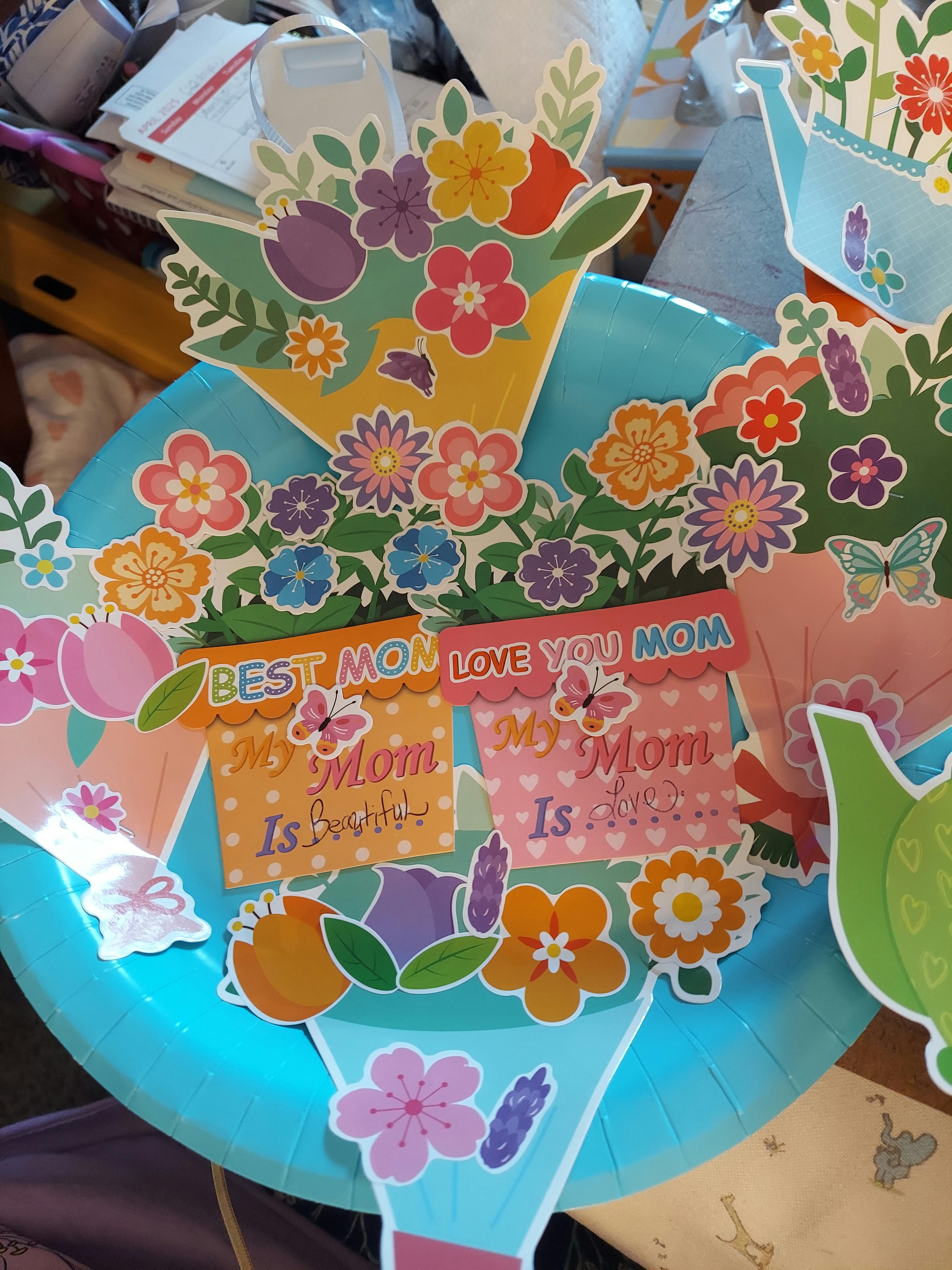 Paper cutouts of flowers and flower pots with "Best Mom" and "Love You Mom" text