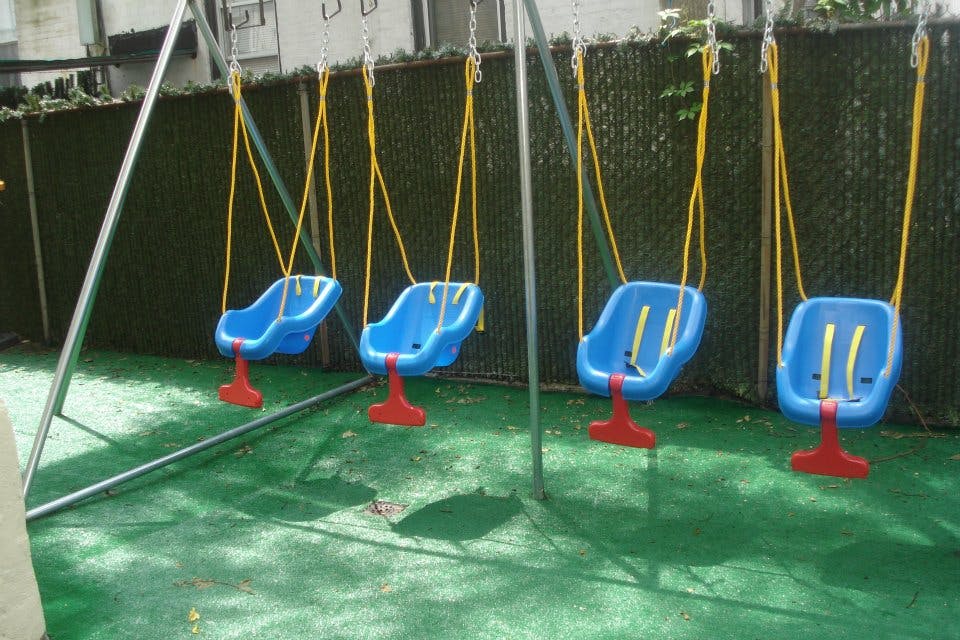 Four empty blue swings on a playground