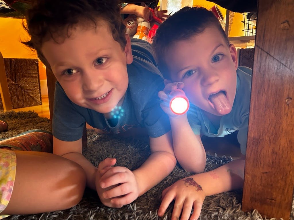 Two children on the floor, one holding a flashlight