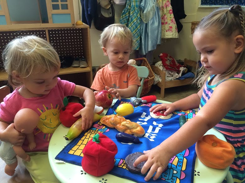 Three children playing with toy food at a table