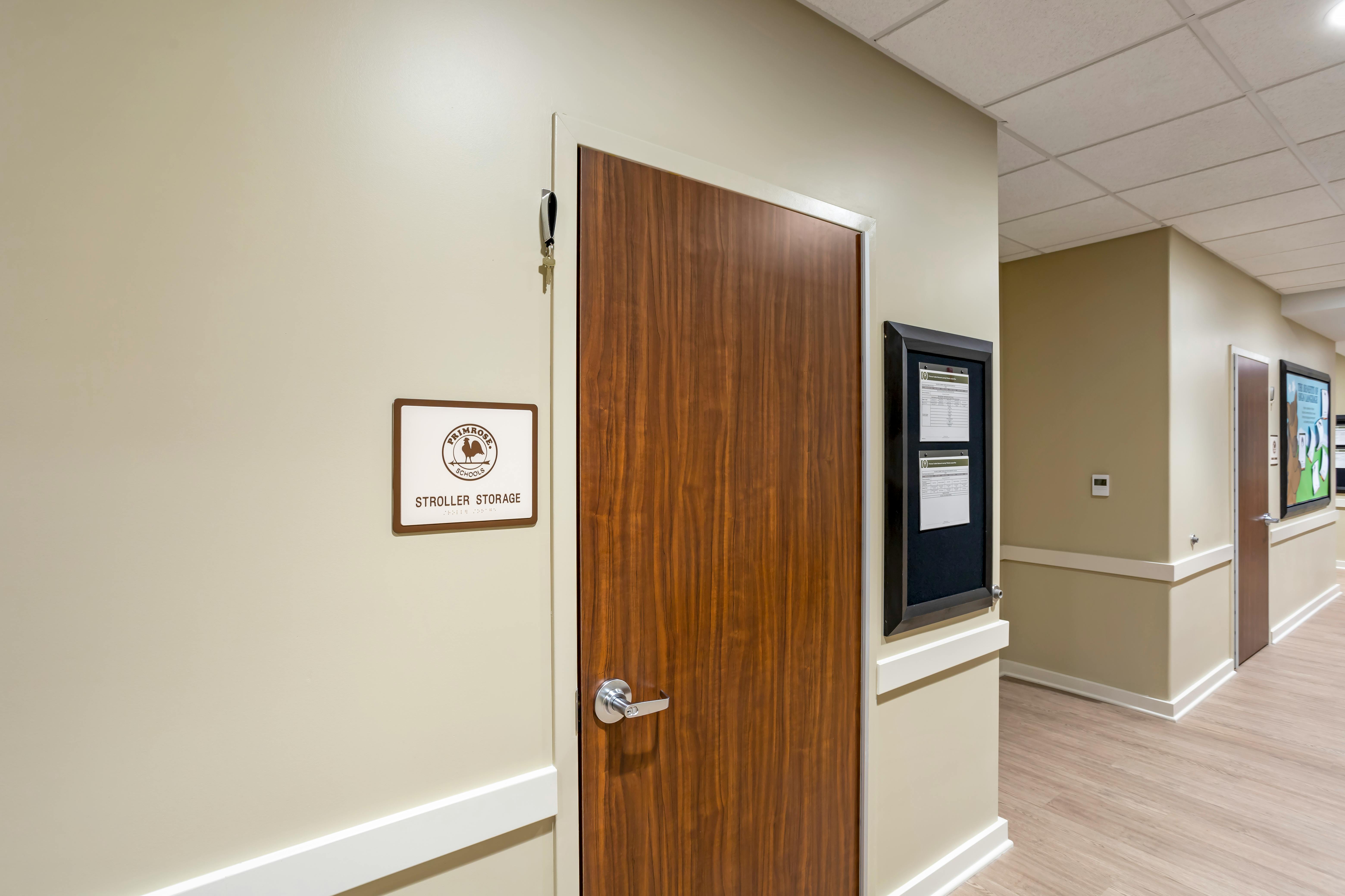 Stroller storage sign next to a wooden door in a hallway