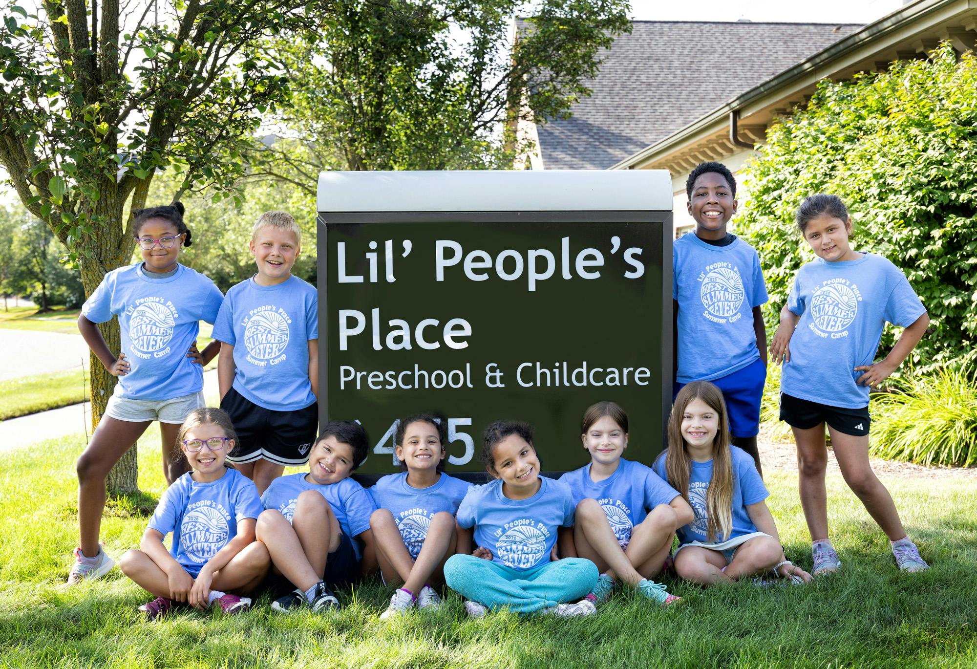 Group of children wearing matching t-shirts posing in front of a building sign