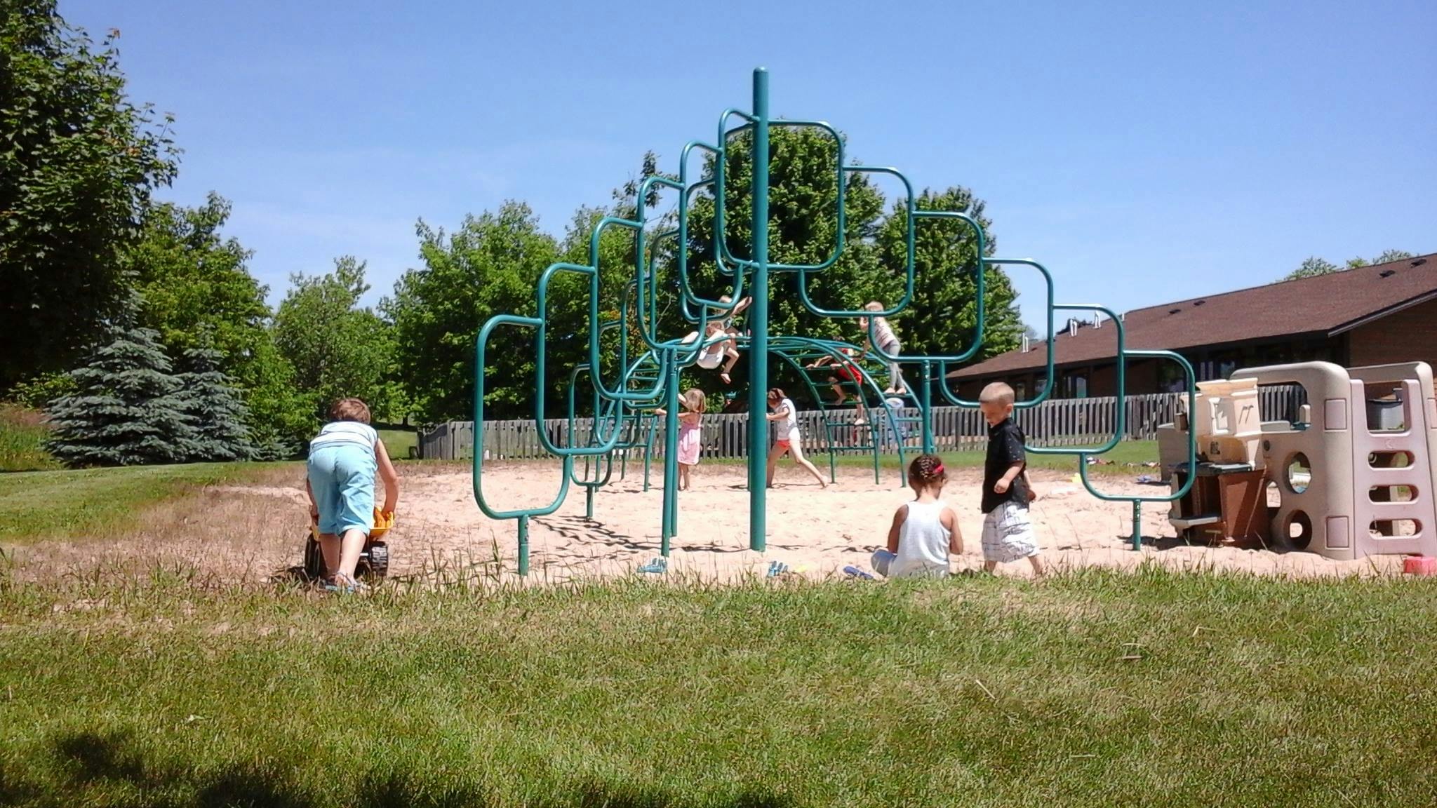 Children playing on playground equipment in a sandy area
