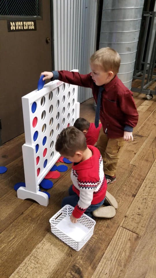Two children playing with a large Connect Four game