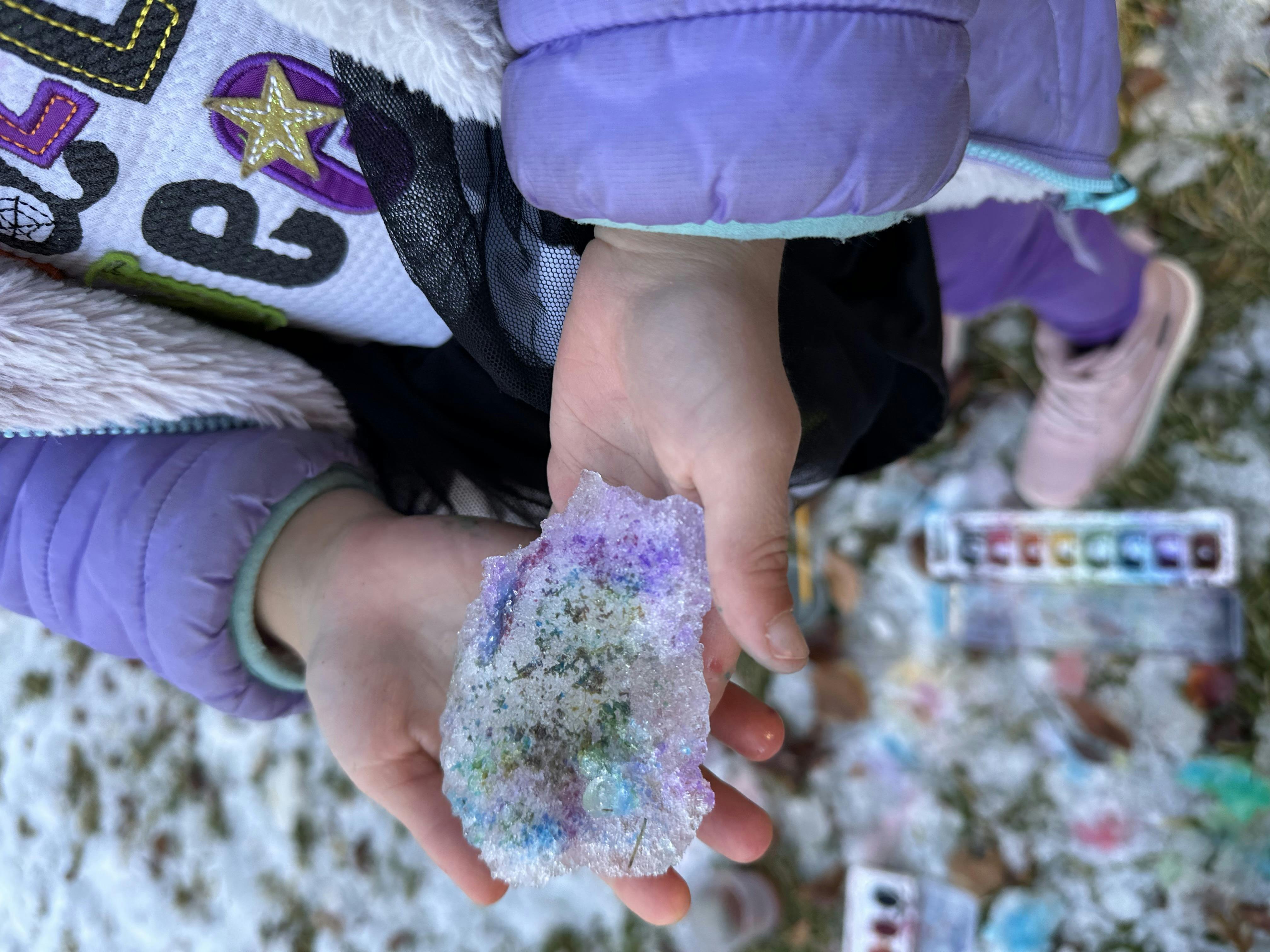 Child holding snow with colorful specks