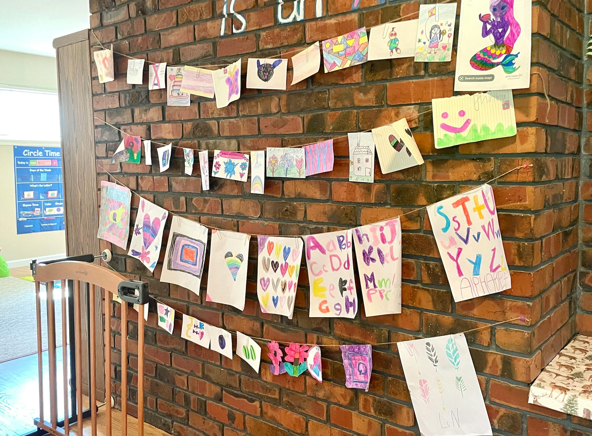 Children's artwork displayed on a brick wall