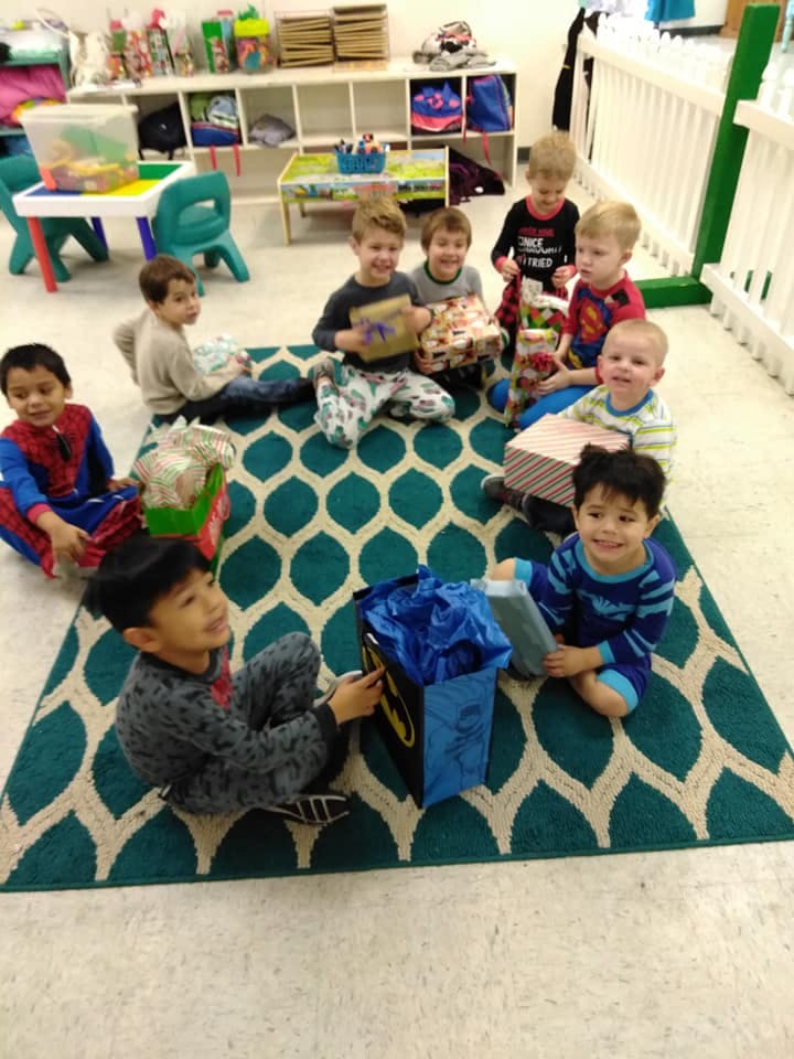 Group of children sitting on a rug opening gifts in a classroom
