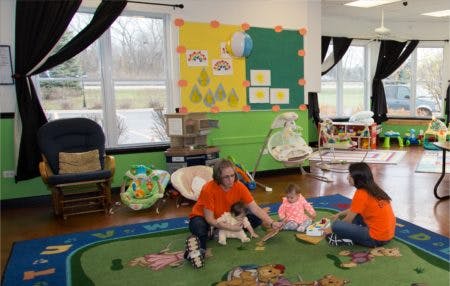 Two people and two children playing on a rug in a room
