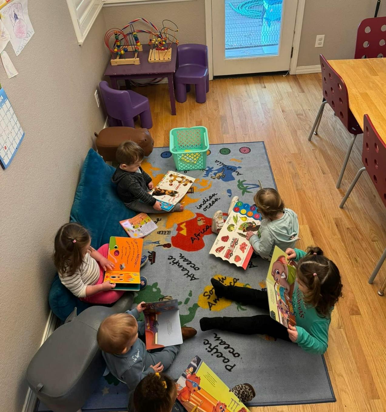 Children sitting on a rug reading books in a classroom