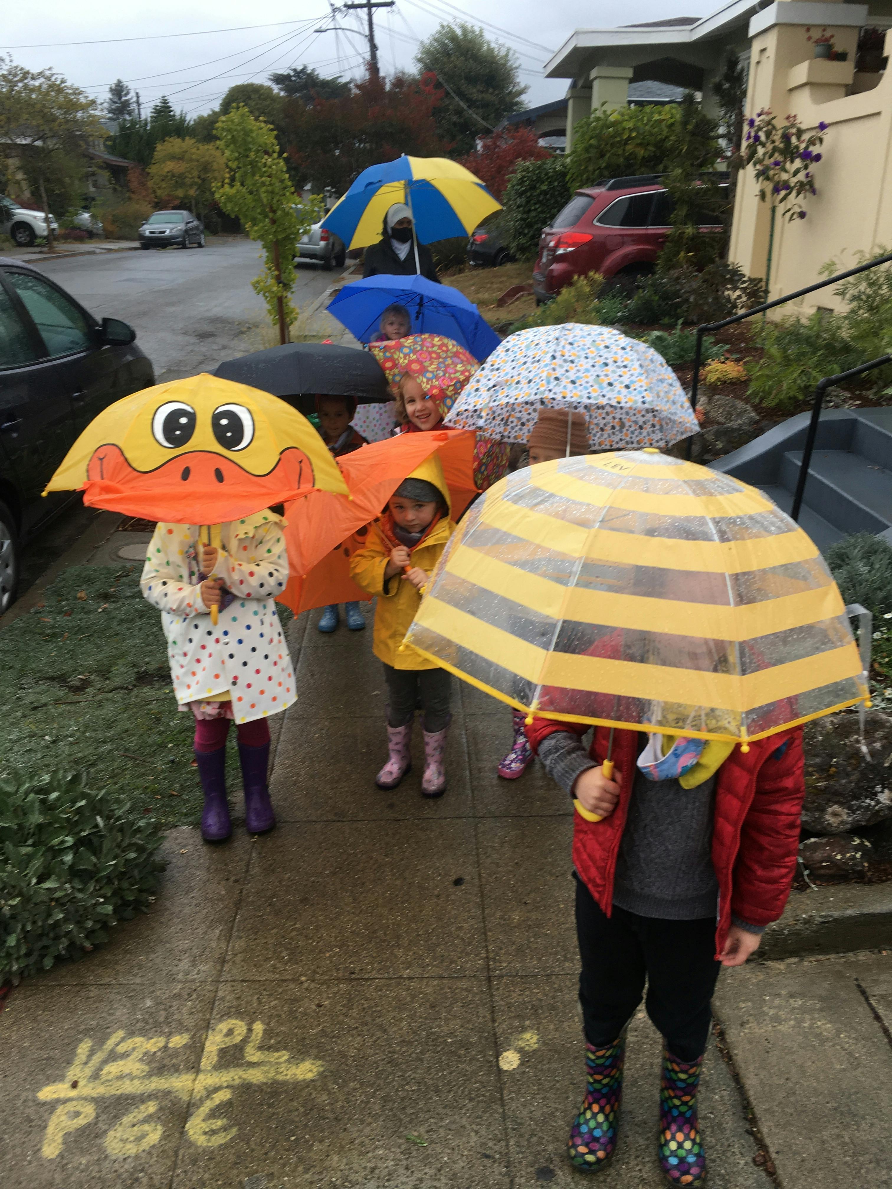 Children holding umbrellas on a sidewalk