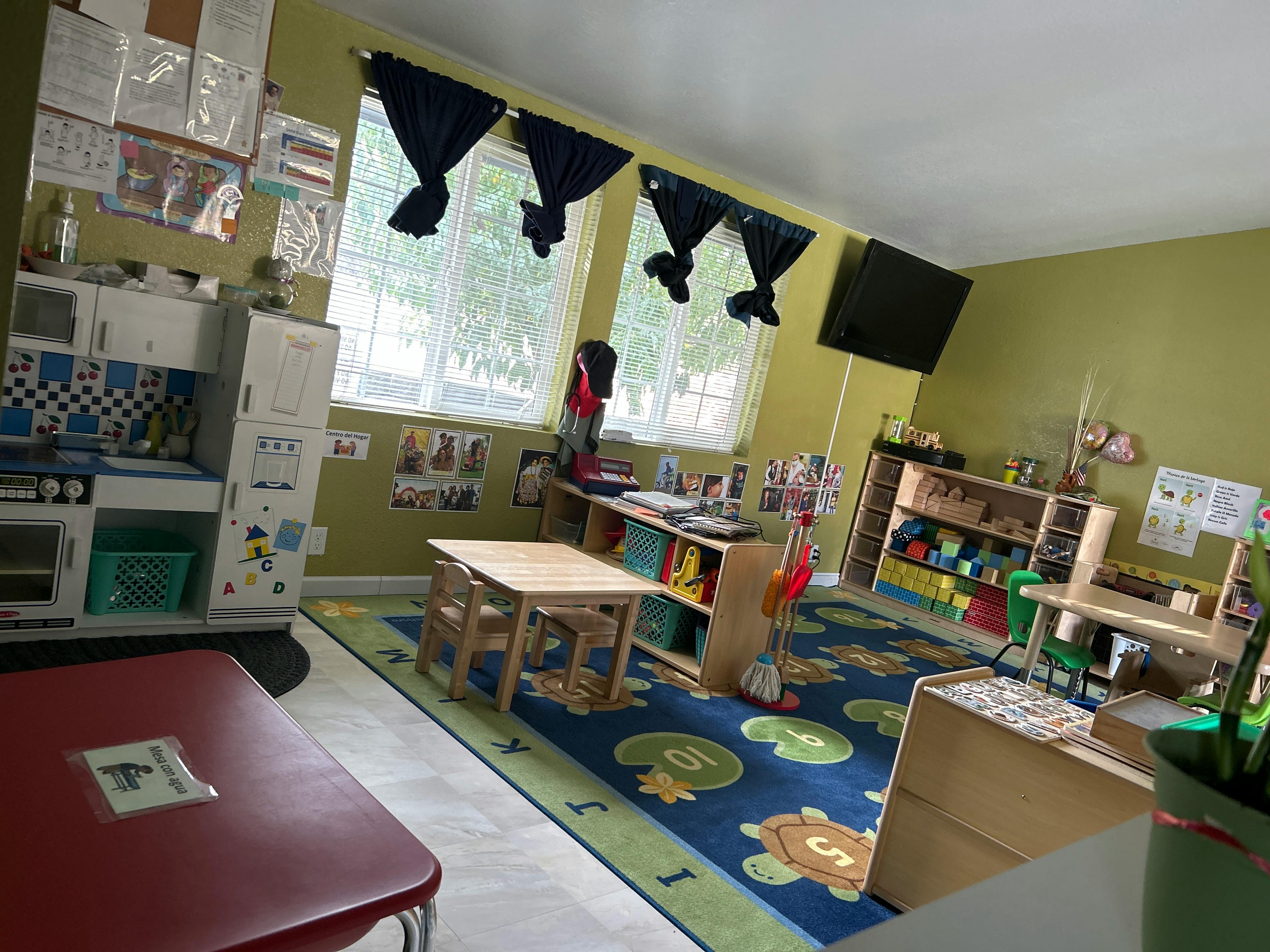 Classroom with small tables, chairs, and play kitchen