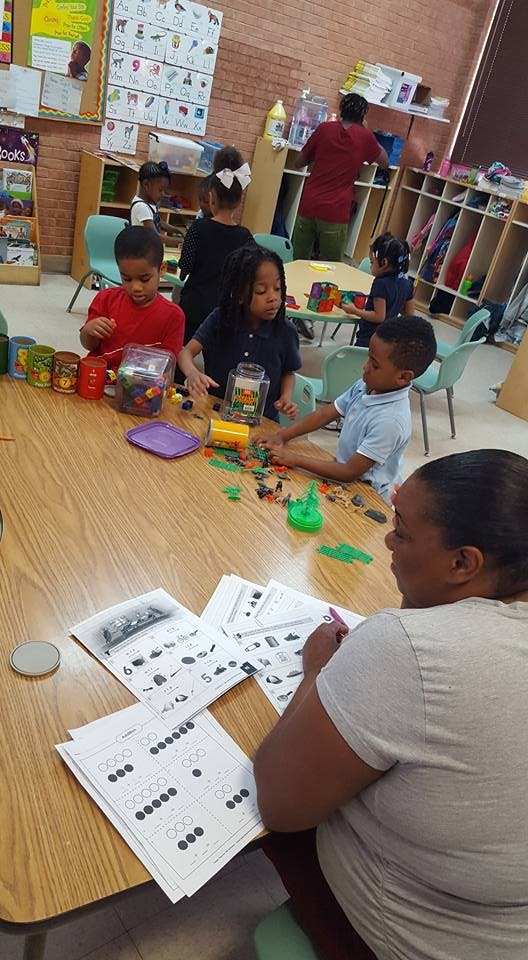 Adult and children in a classroom with learning materials