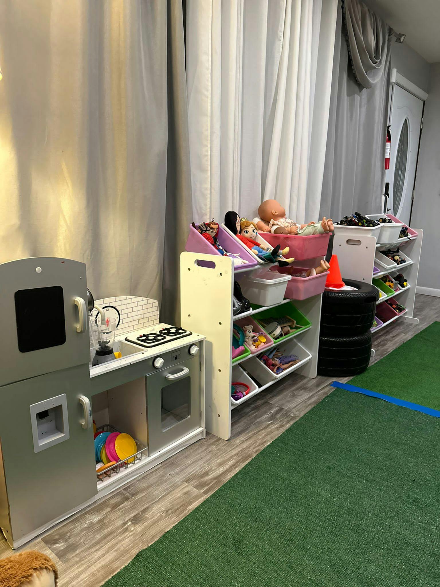 Play kitchen and toy storage shelves in a room with green carpet