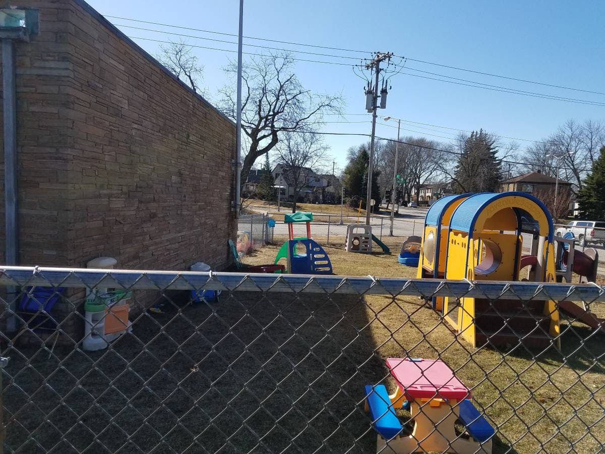 Playground with yellow and blue play structure behind a chain link fence