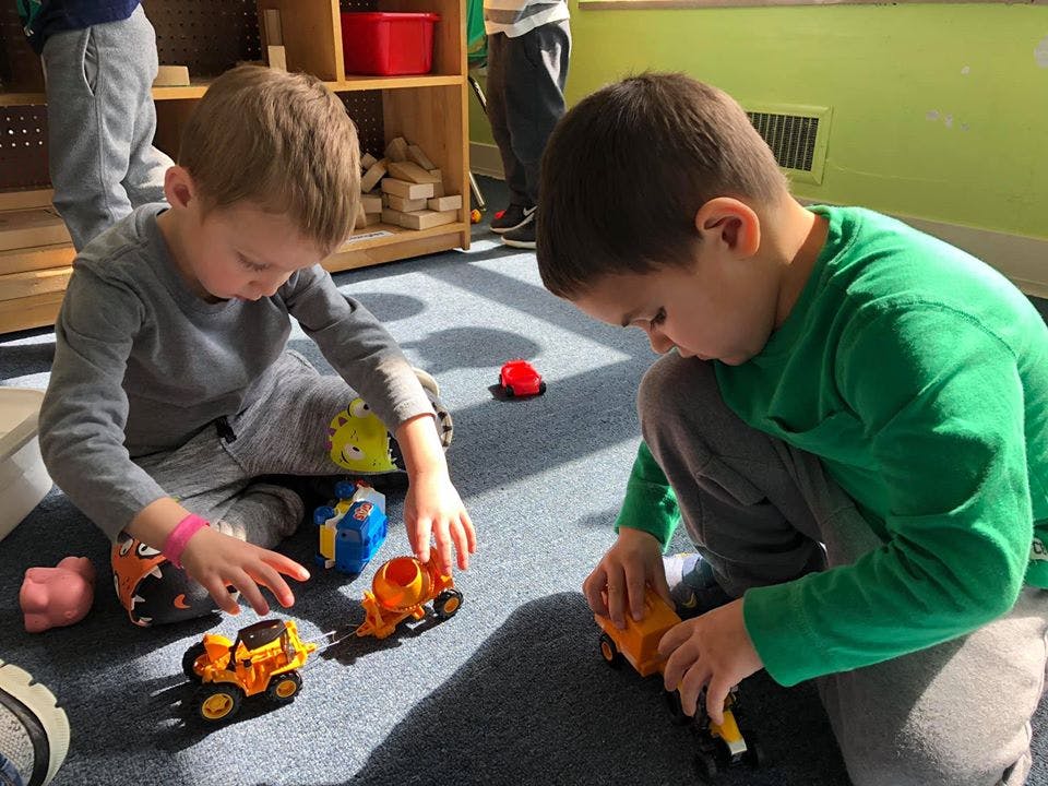 Two children playing with toy trucks on the floor