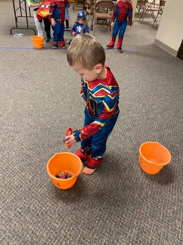 Child in costume picking up items from a bucket