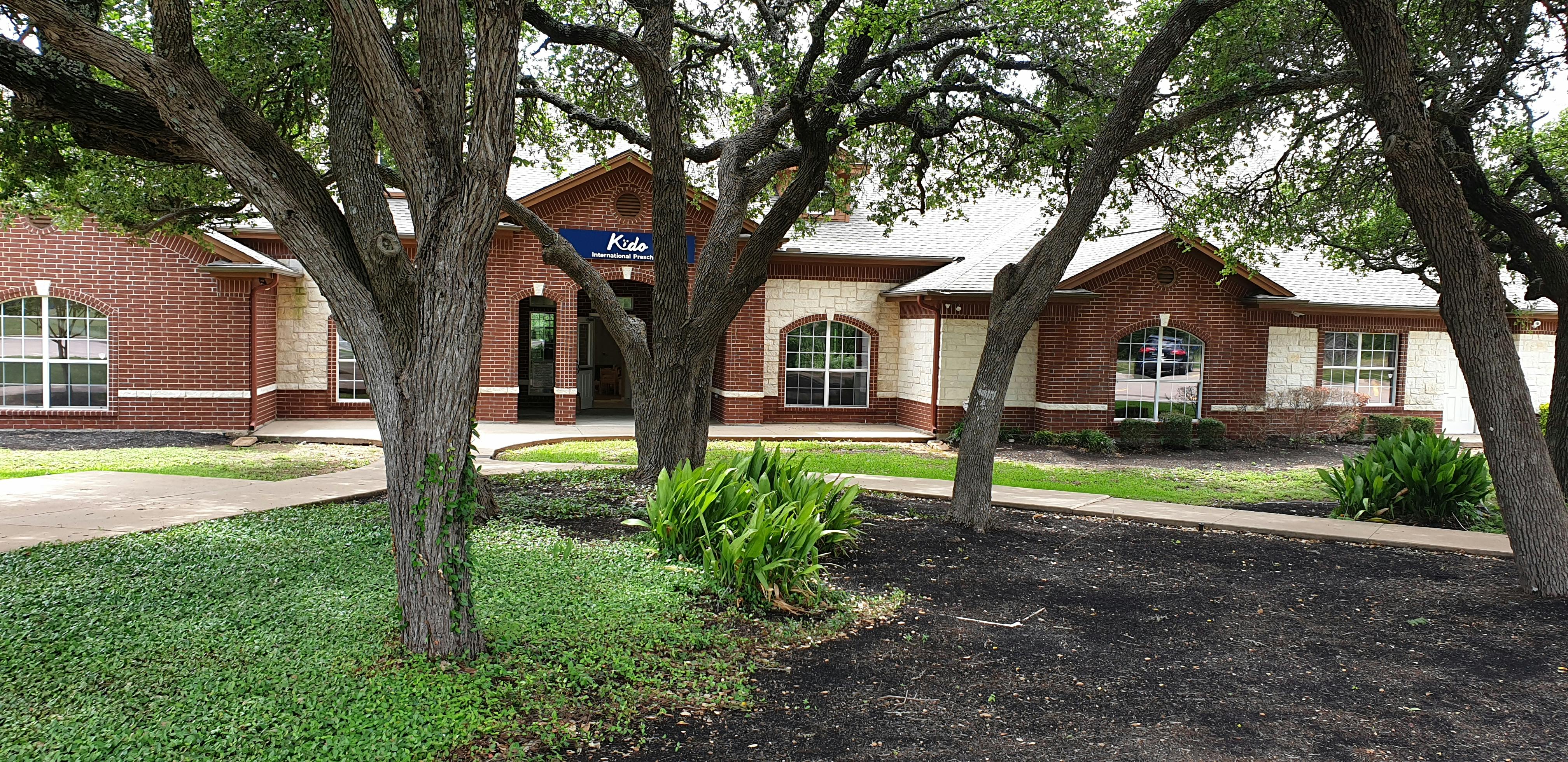 Building with brick and cream siding seen through trees