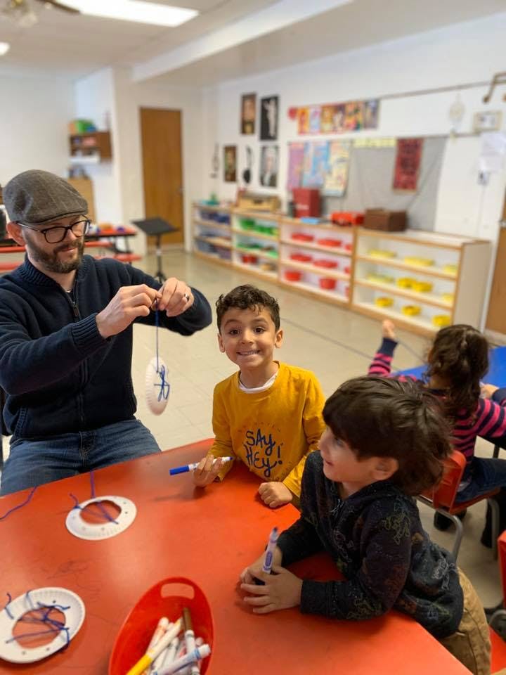 Adult and children at a table doing an art activity