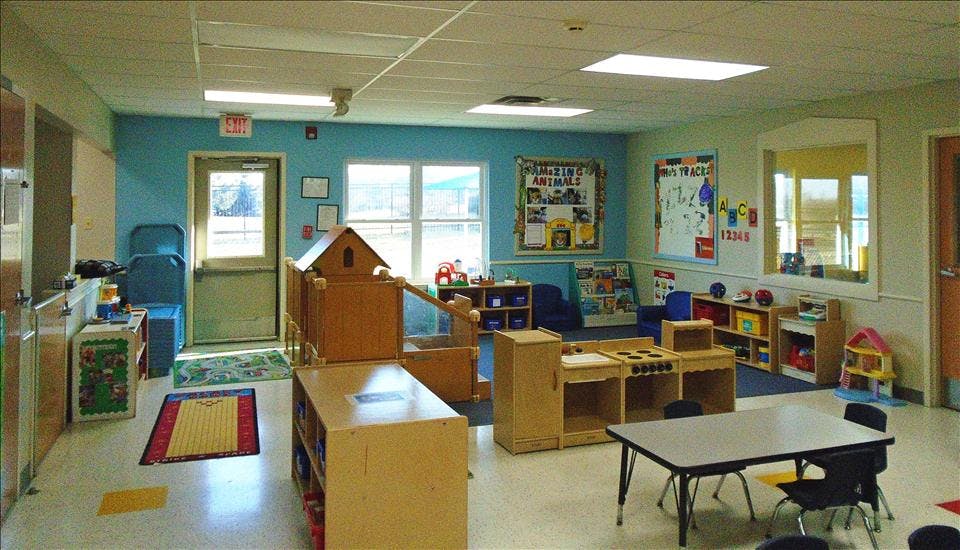 A classroom with light blue walls, child-sized furniture, and toys