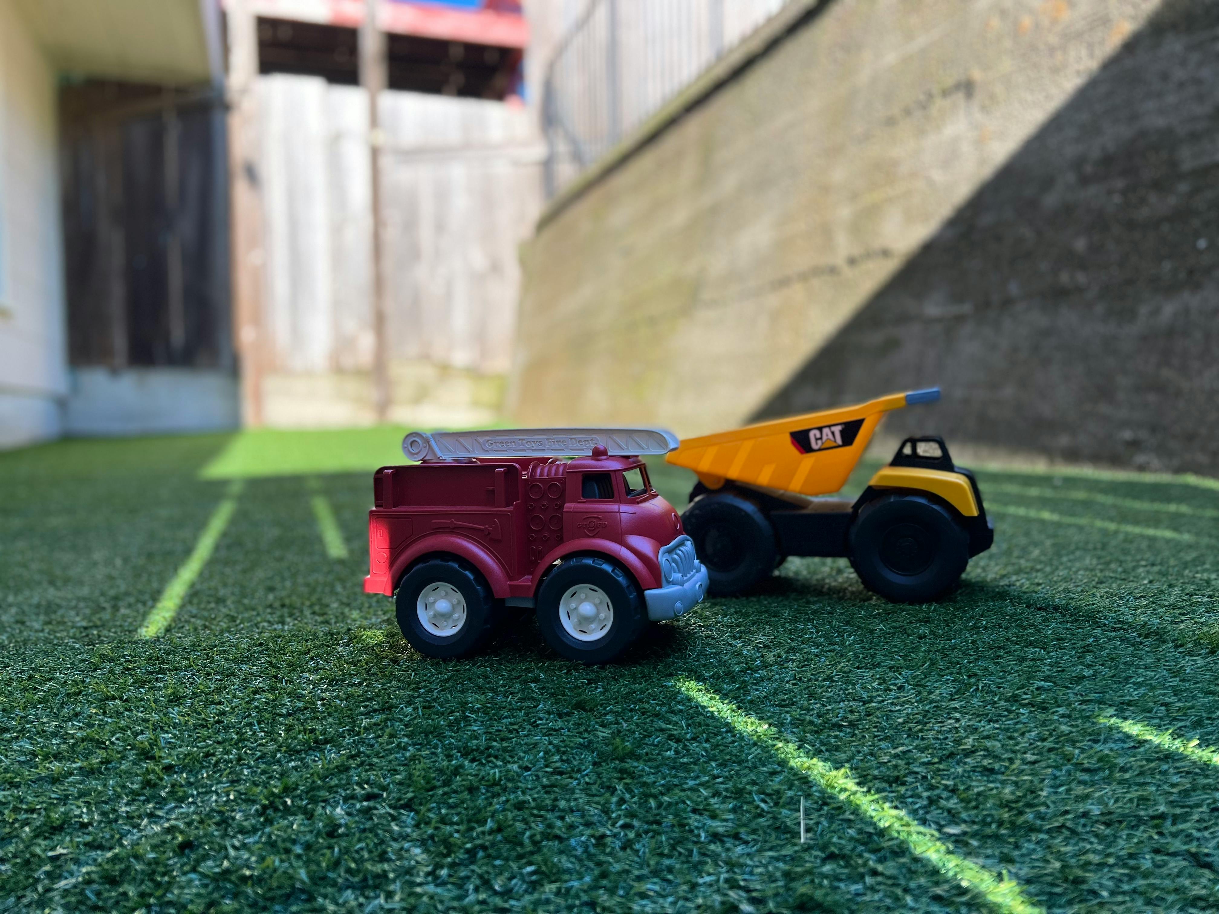 Toy fire truck and dump truck on artificial grass