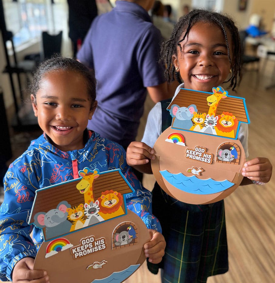 Two children holding Noah's Ark crafts with "God Keeps His Promises" text