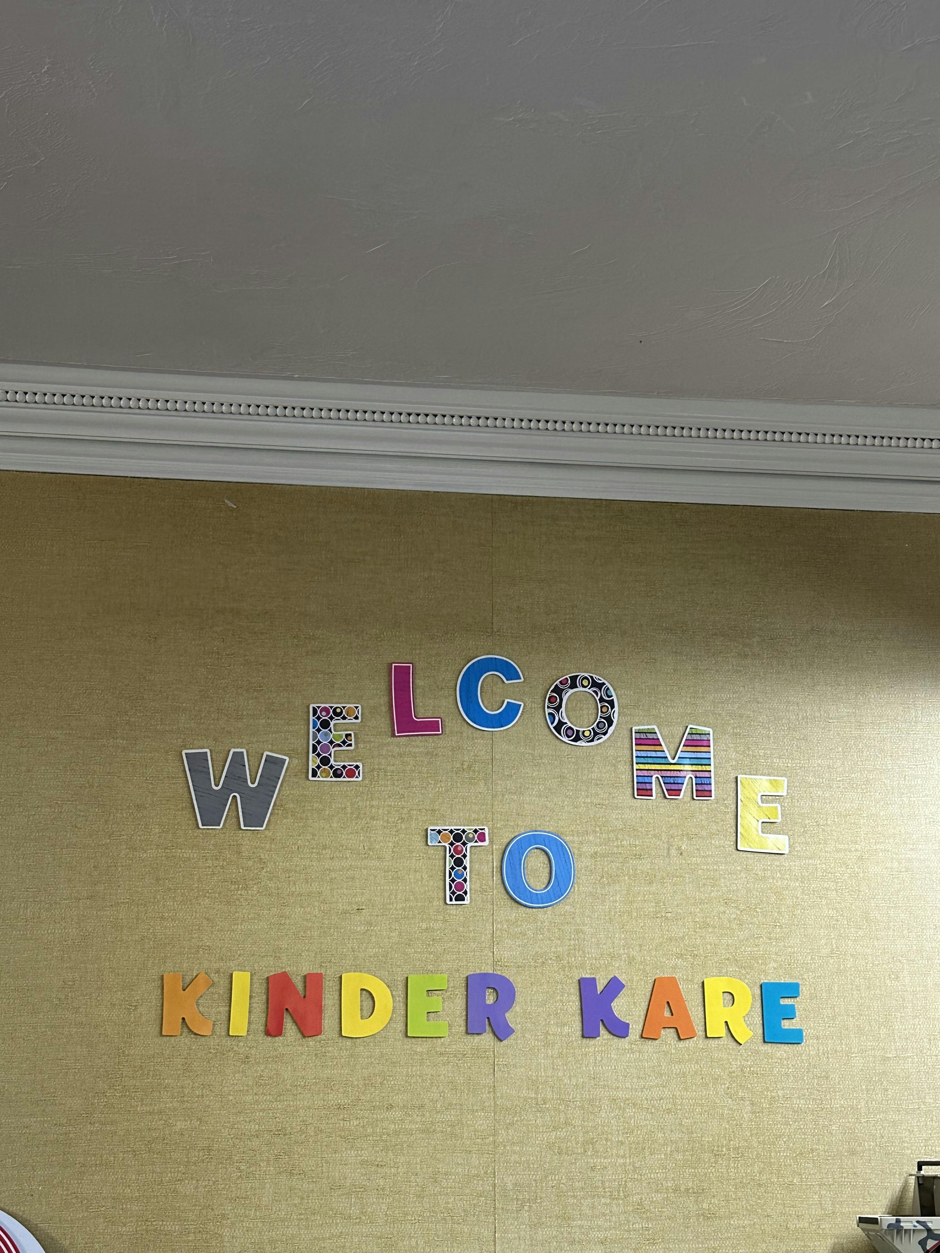 Colorful letters spelling "WELCOME TO KINDER KARE" on a wall