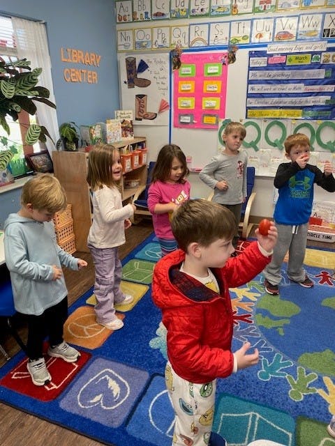 Group of children standing on a colorful classroom rug
