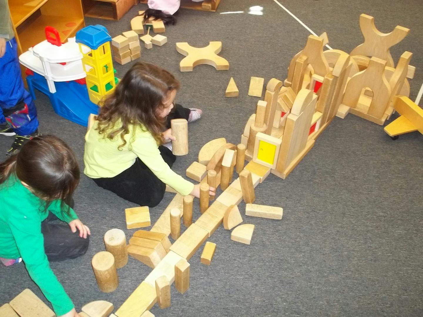 Two children playing with wooden blocks on the floor