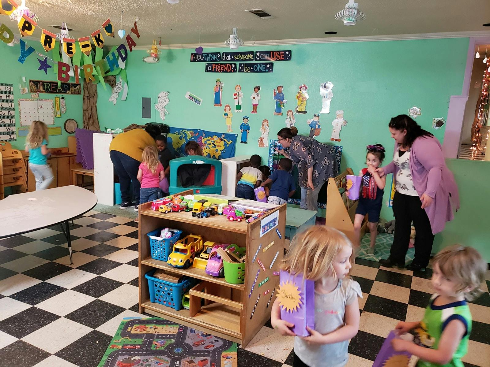 Adults and children in a classroom with toys and decorations