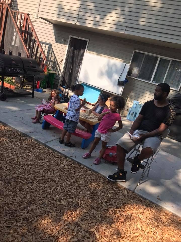 Person sitting with children around a picnic table outdoors