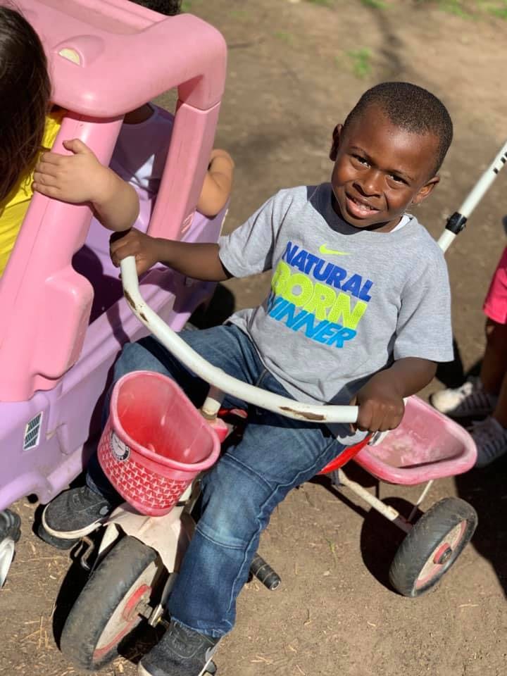 Child on a tricycle with a pink basket