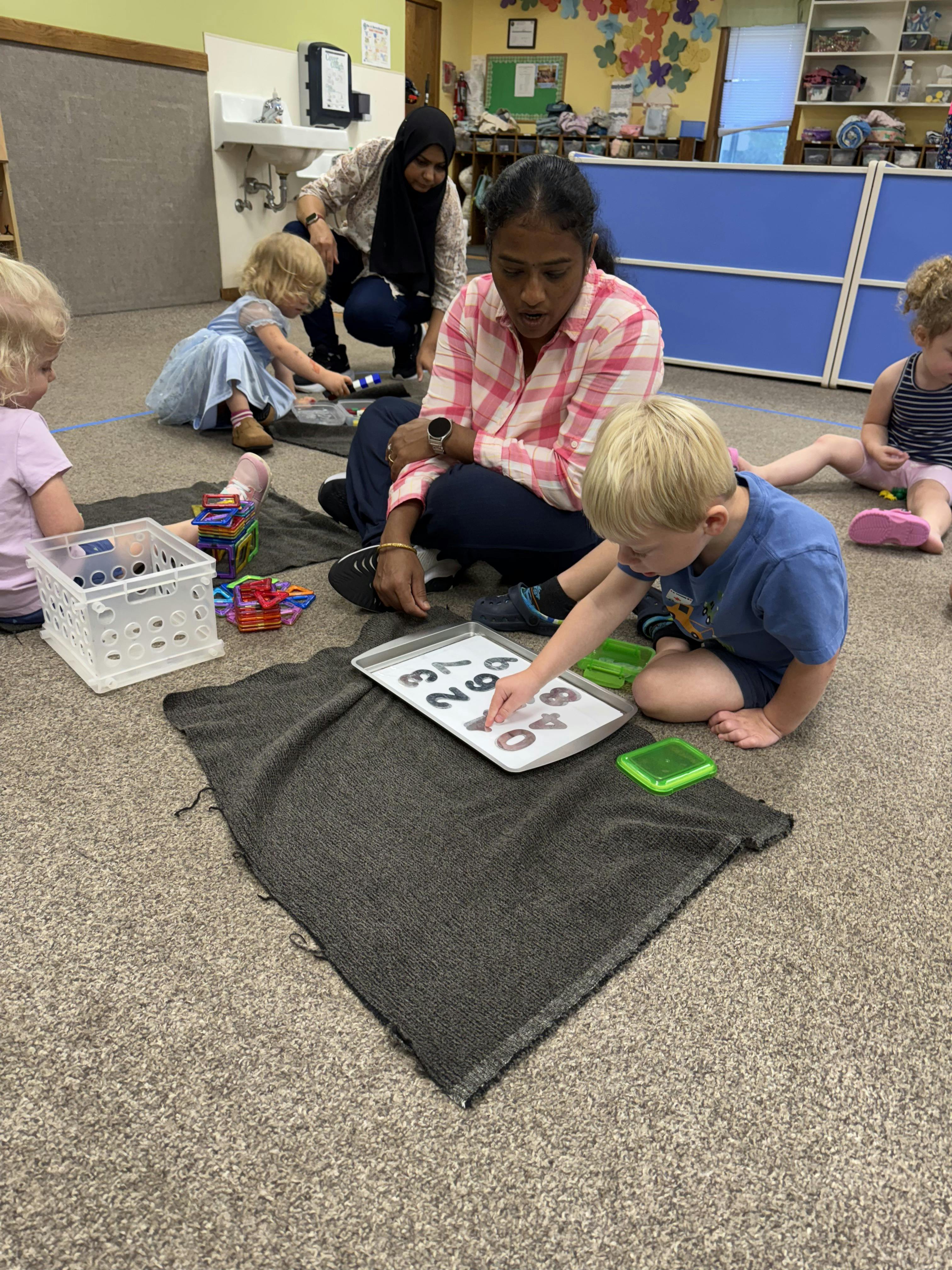 Adult and children on floor, child playing with number magnets