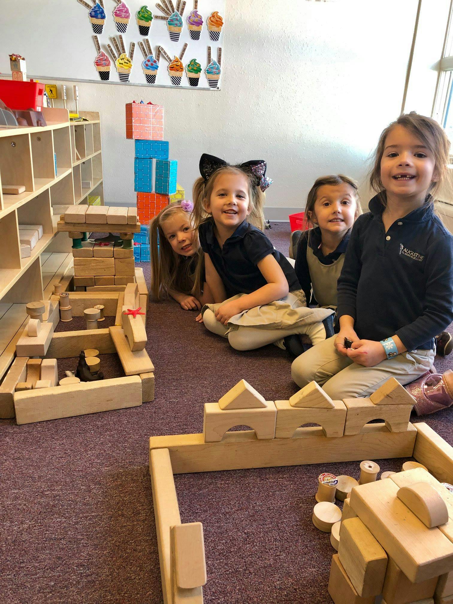 Four children sitting on the floor with wooden blocks