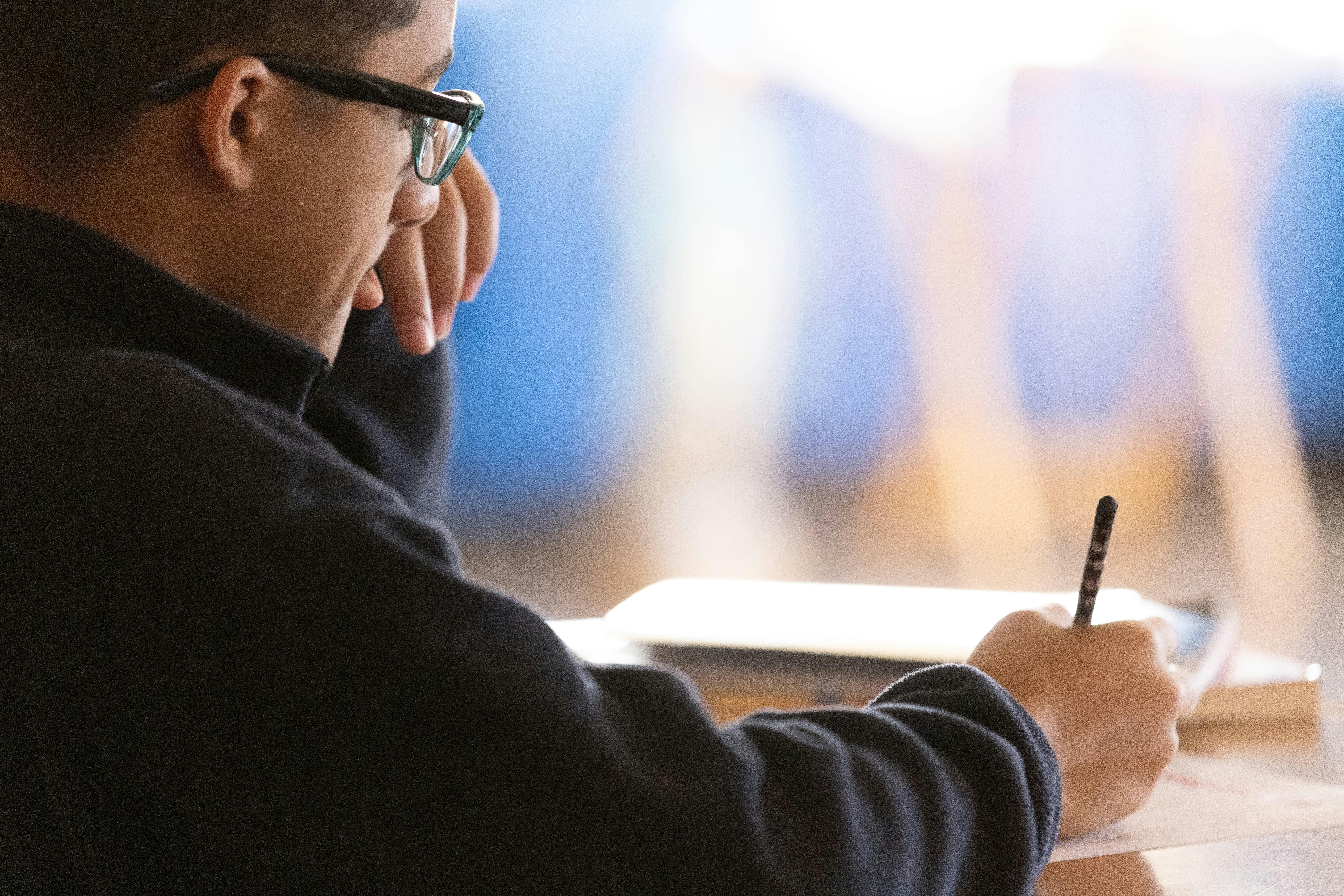 Person in glasses writing in a notebook