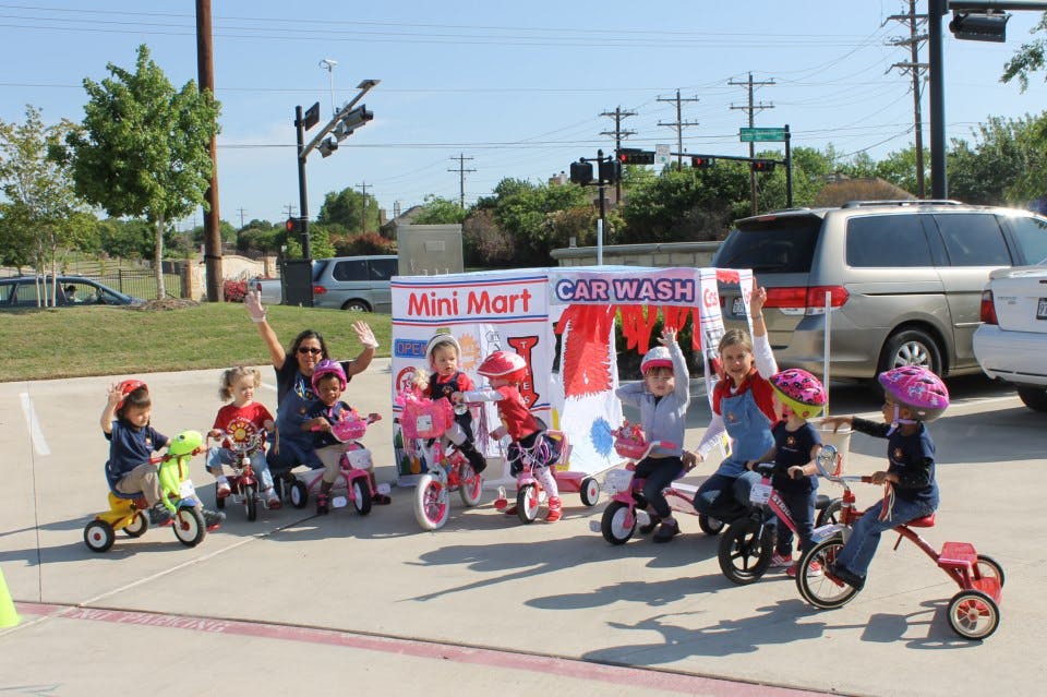 Adult and children on tricycles near a "Mini Mart Carwash" stand