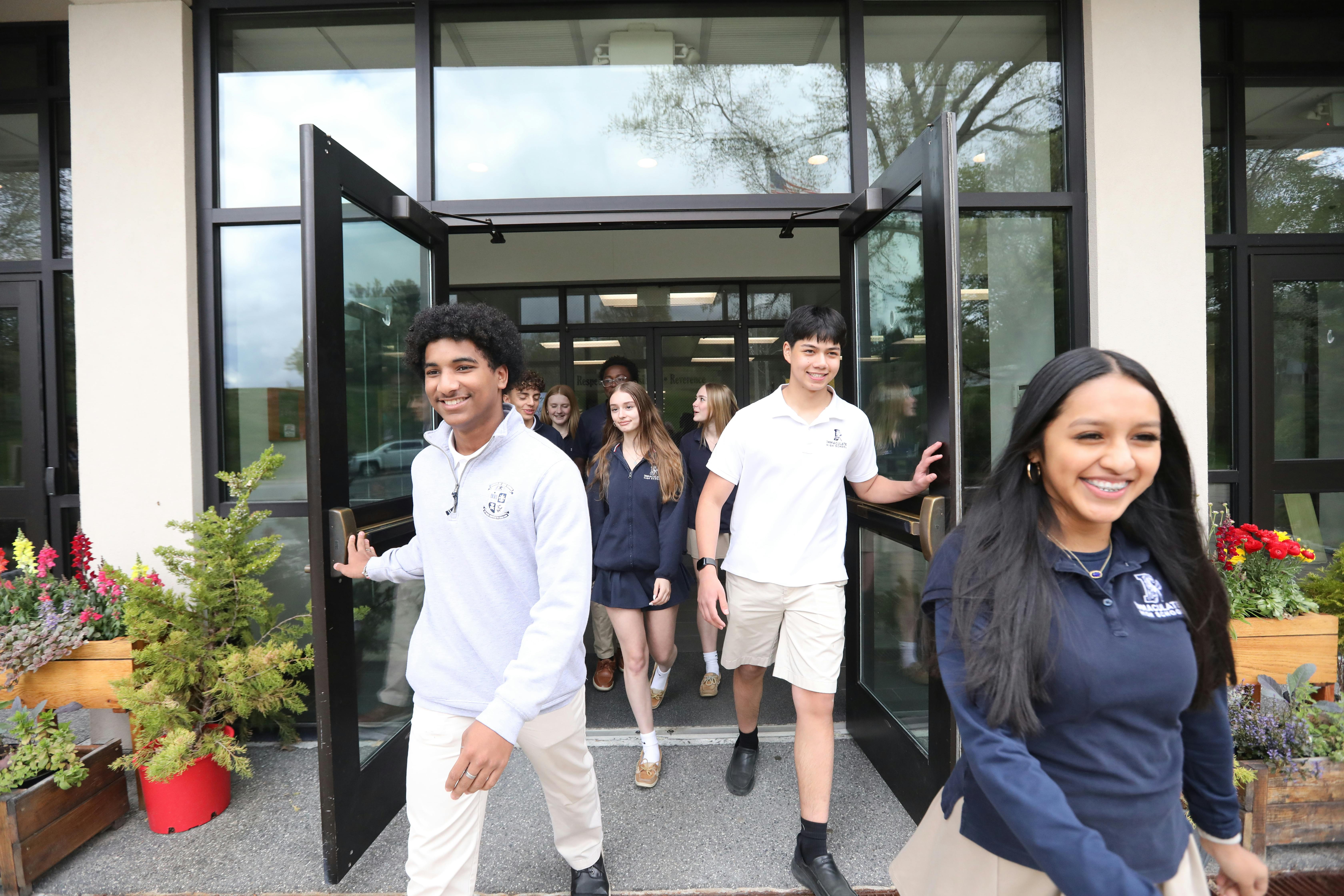 Group of teens walking out of a school building entrance