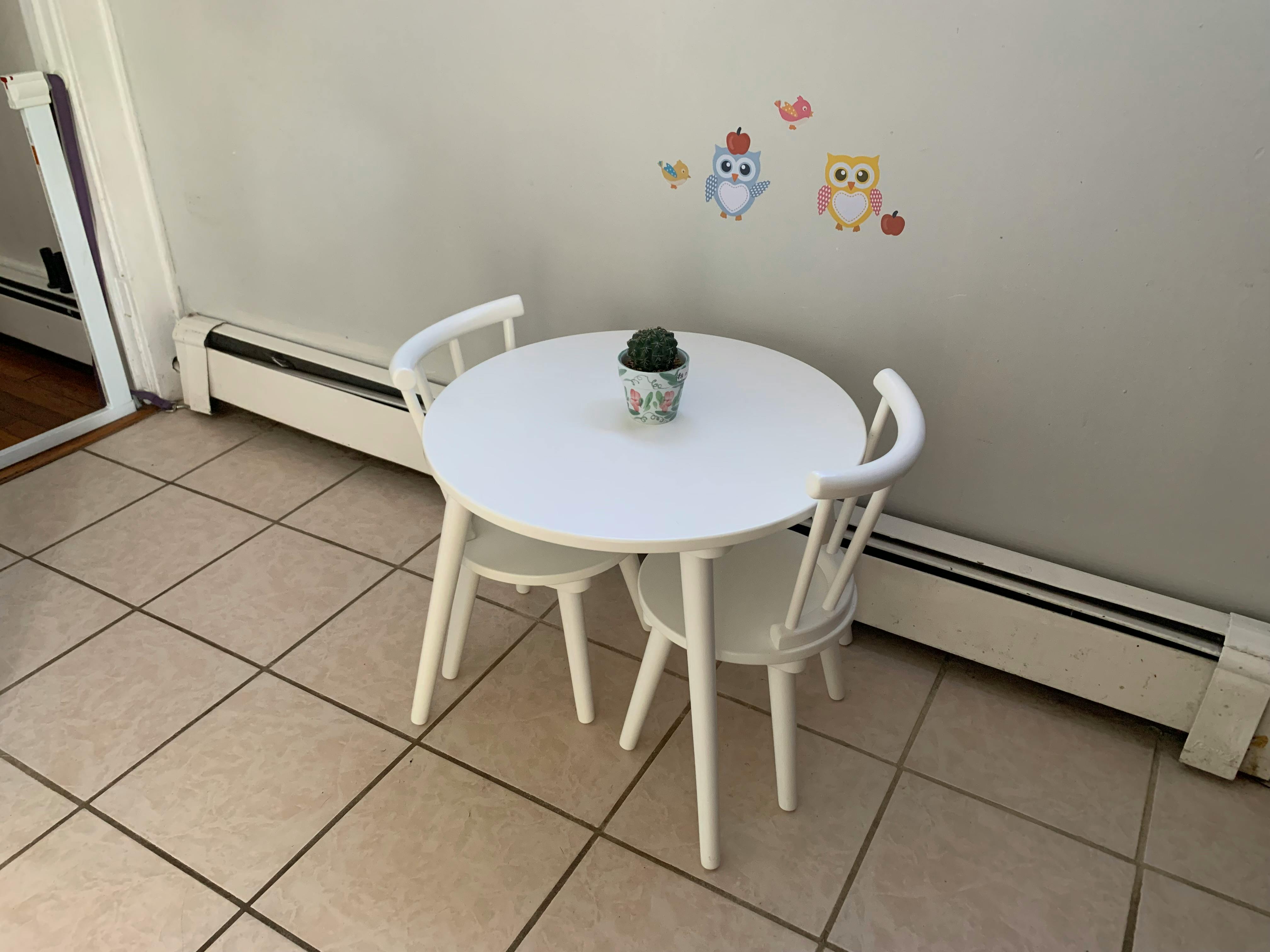 White round table with two chairs and a small plant