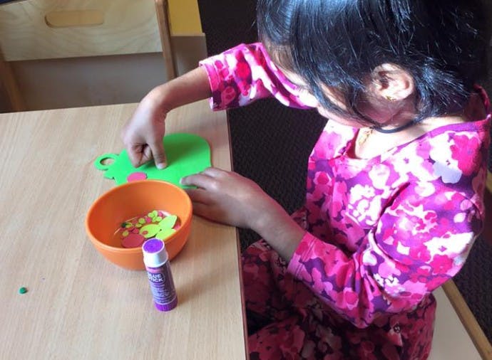 Child doing a craft with paper cutouts and glue stick