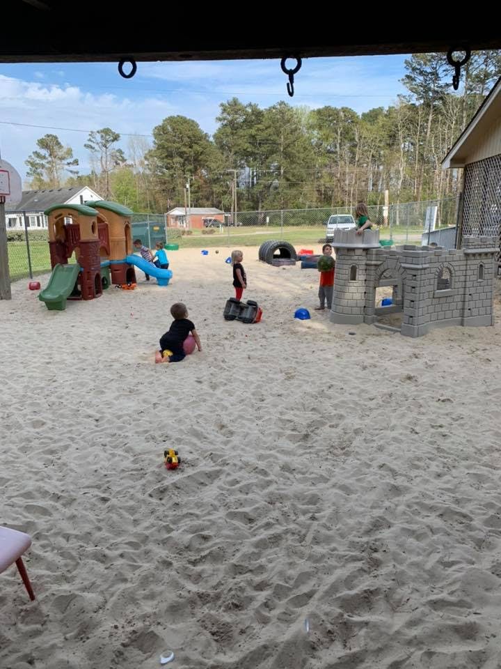 Children playing in a large sandbox with playground equipment